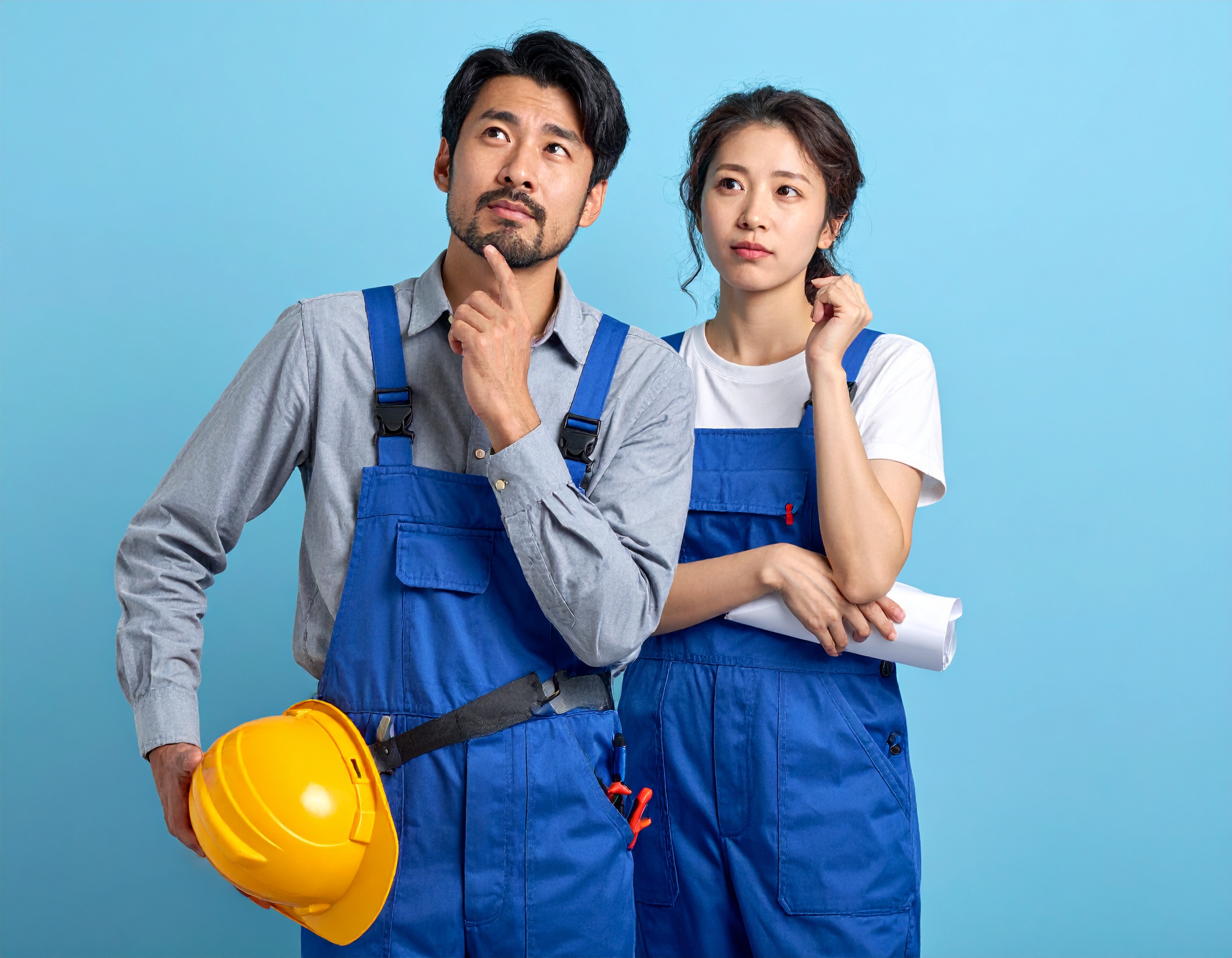 第二種電気工事士を取得するべきか悩んでいる日本人男性と女性。 資格教材や工具を前に考え込んでいる様子。 将来への不安と期待の両方を感じる自然な表情。 明るく清潔感のある教育系メディア向け写真。